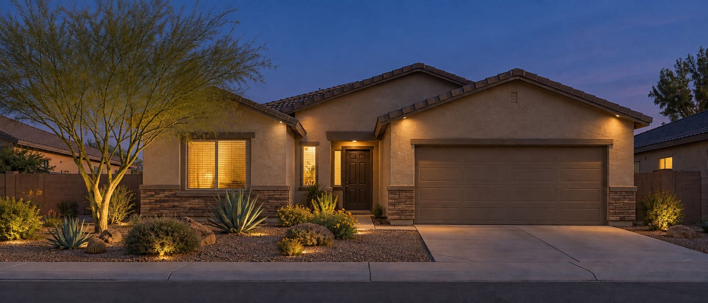 A desert home at dusk with interior, soffit, and landscape lighting on